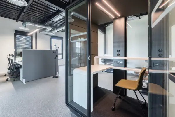 Un bureau moderne avec des cabines acoustiques et du mobilier flex office, idéal pour la concentration.