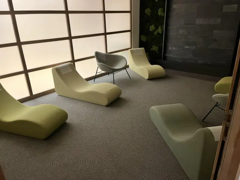 Un espace d'accueil moderne avec des chaises longues confortables et un mur végétal apaisant.